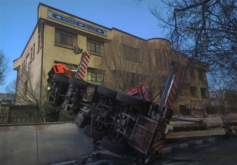 واژگونی جرثقیل به یک مدرسه و ۳ خودرو در تهران خسارت زد/ راننده مصدوم شد